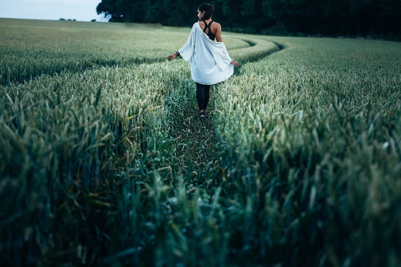 une femme marchant dans un champ de blé. Ni le gluten ni les fructanes ne posent problème au toucher heureusement !